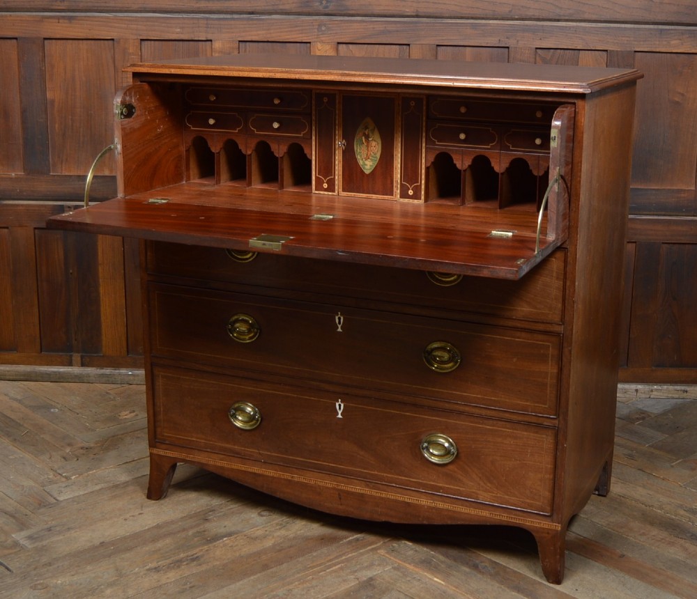 A Regency mahogany secretaire chest featuring oval inlay on the top drawer, brass oval handles, bone escutcheons, and splayed bracket feet. View II