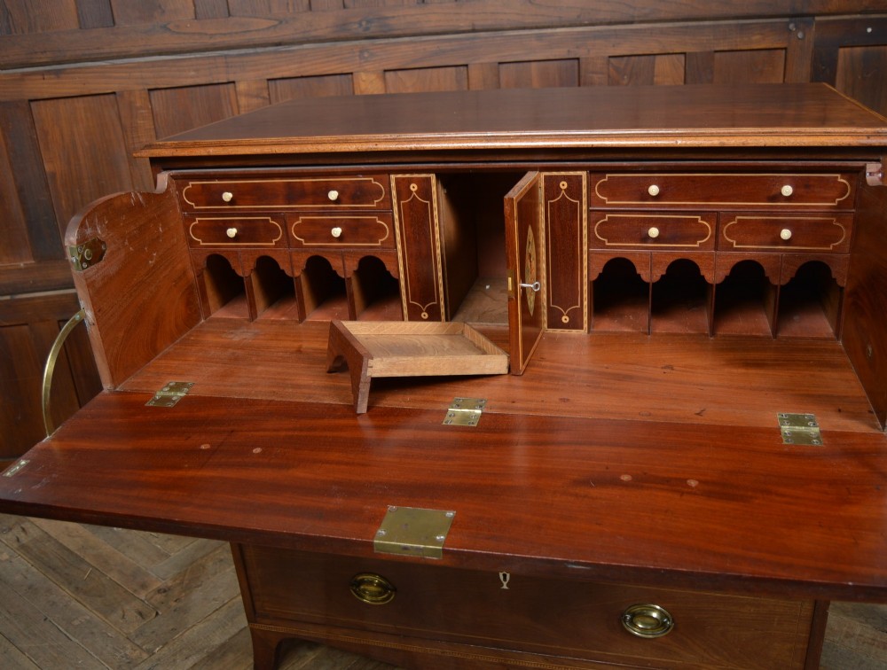 A Regency mahogany secretaire chest featuring oval inlay on the top drawer, brass oval handles, bone escutcheons, and splayed bracket feet. View III