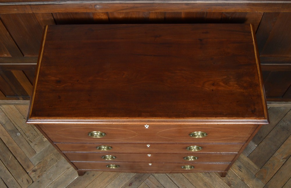 A Regency mahogany secretaire chest featuring oval inlay on the top drawer, brass oval handles, bone escutcheons, and splayed bracket feet. View VI