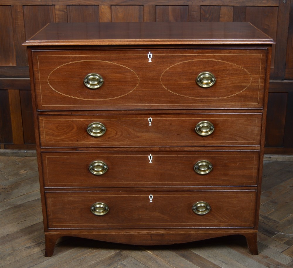 A Regency mahogany secretaire chest featuring oval inlay on the top drawer, brass oval handles, bone escutcheons, and splayed bracket feet. View XII