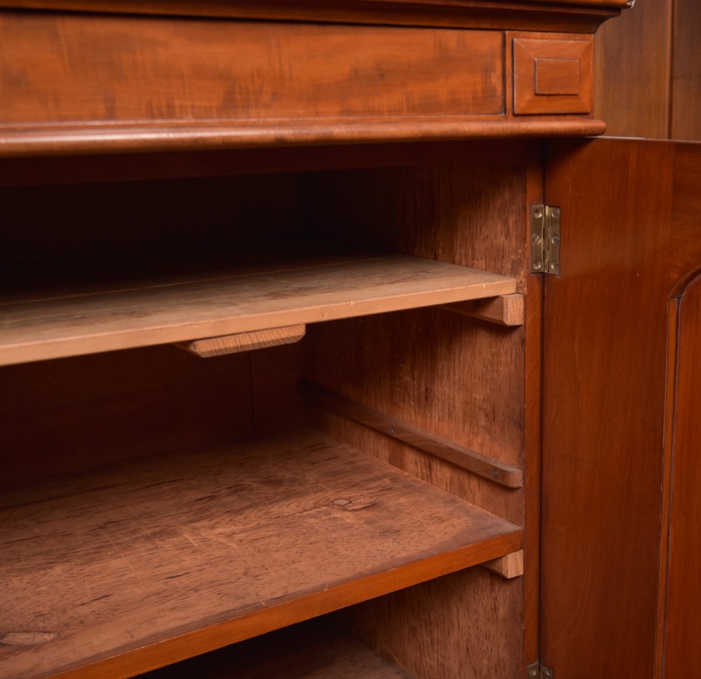 A Victorian mahogany two-part bookcase featuring a moulded cornice, two upper glazed doors with adjustable shelves, and a lower base with two arched panelled cupboard doors. View II