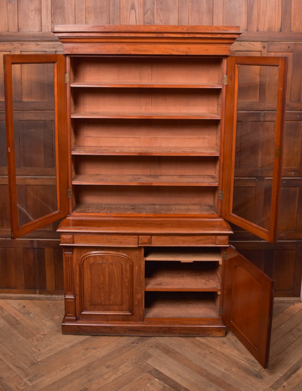 A Victorian mahogany two-part bookcase featuring a moulded cornice, two upper glazed doors with adjustable shelves, and a lower base with two arched panelled cupboard doors. View III