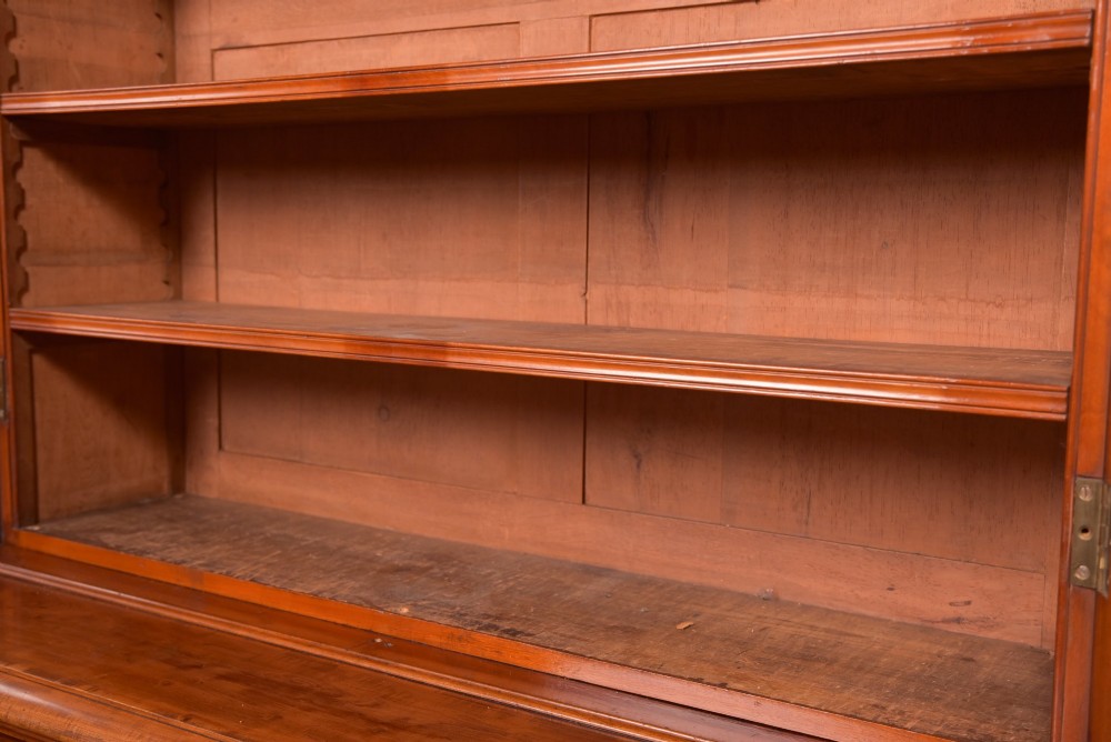 A Victorian mahogany two-part bookcase featuring a moulded cornice, two upper glazed doors with adjustable shelves, and a lower base with two arched panelled cupboard doors. View VI