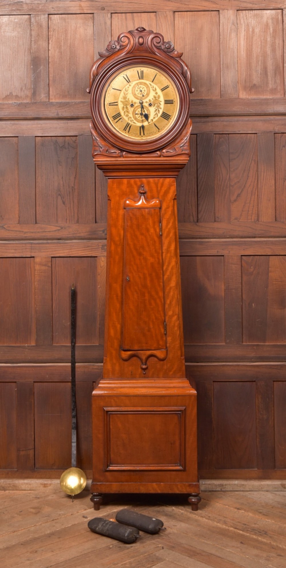 A Victorian Scottish mahogany drumhead longcase clock featuring a circular hood with carved scrollwork, a brass dial, and a flame mahogany trunk.