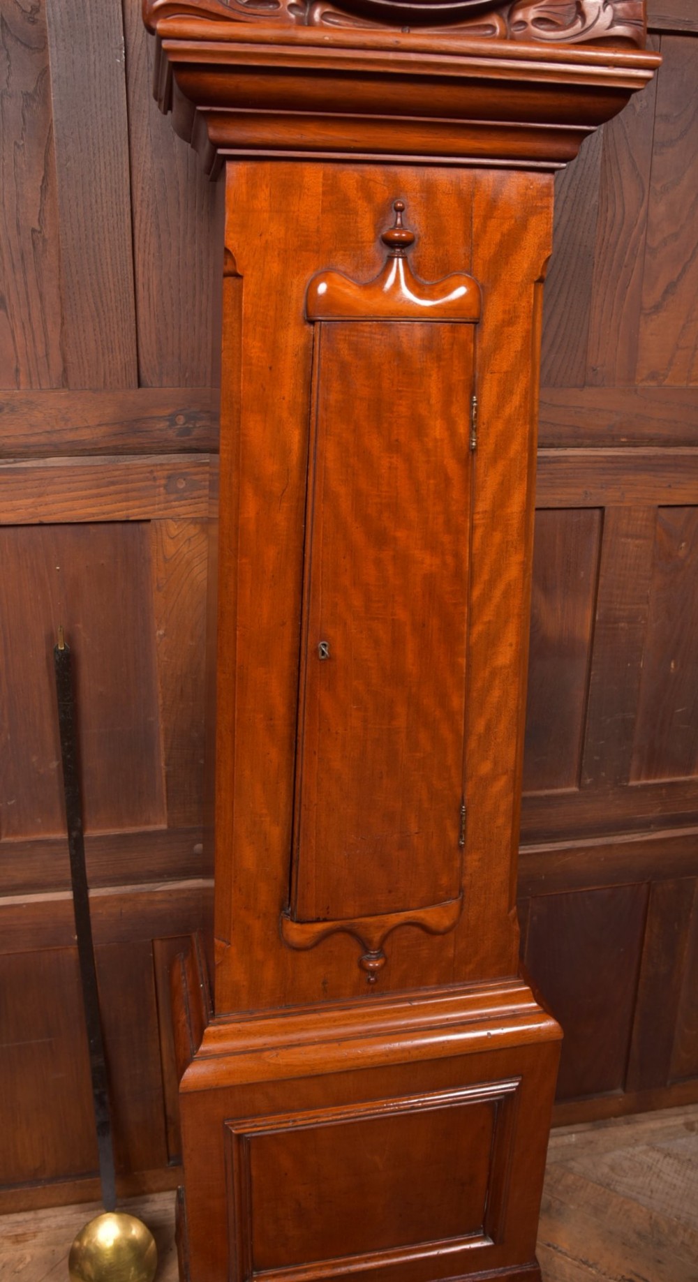 A Victorian Scottish mahogany drumhead longcase clock featuring a circular hood with carved scrollwork, a brass dial, and a flame mahogany trunk. View VII