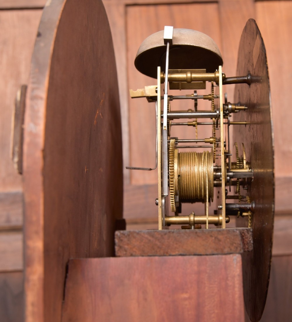 A Victorian Scottish mahogany drumhead longcase clock featuring a circular hood with carved scrollwork, a brass dial, and a flame mahogany trunk. View XIV