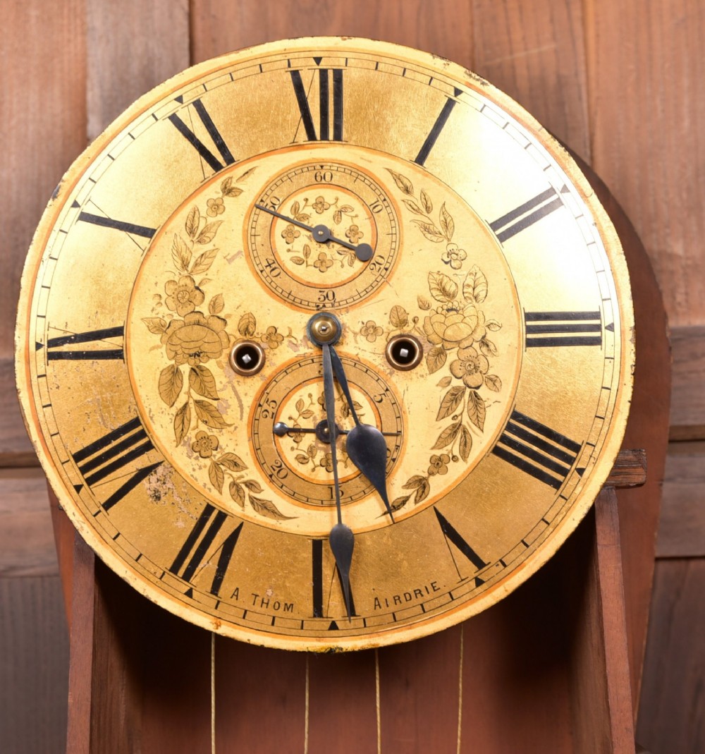 A Victorian Scottish mahogany drumhead longcase clock featuring a circular hood with carved scrollwork, a brass dial, and a flame mahogany trunk. View XV