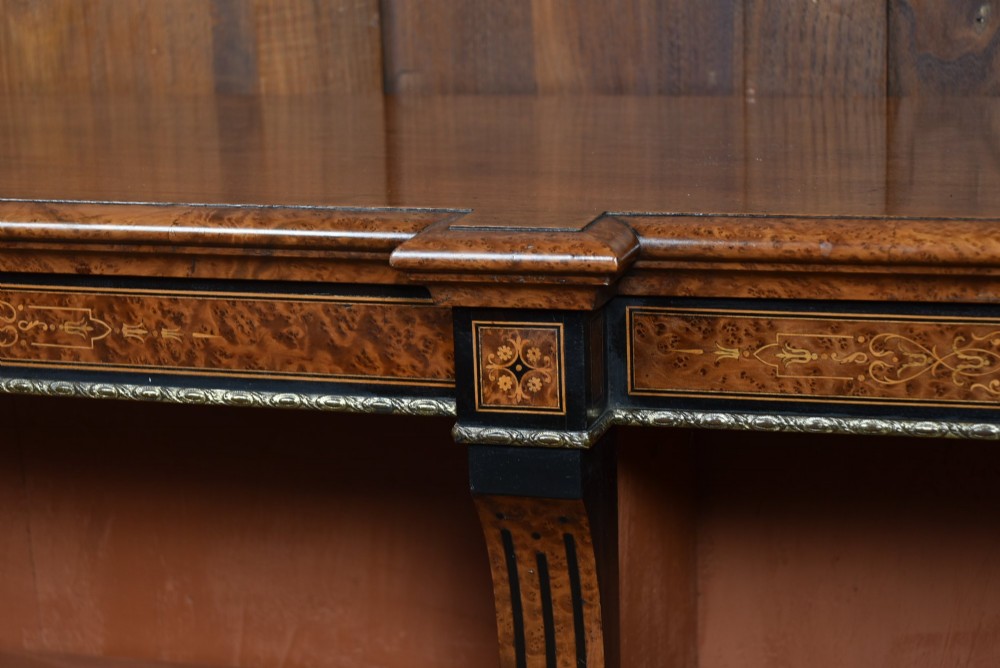 A low Victorian open bookcase featuring three sections of open shelving, rich amboyna wood veneer, ebonised borders, and delicate marquetry inlays. View IV