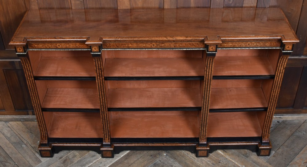 A low Victorian open bookcase featuring three sections of open shelving, rich amboyna wood veneer, ebonised borders, and delicate marquetry inlays. View IX
