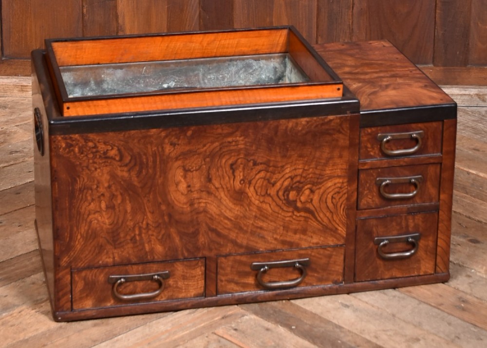 A traditional Japanese wooden hibachi brazier featuring rich figured wood grain, a copper-lined inner well, multiple small drawers, and iron bail handles.