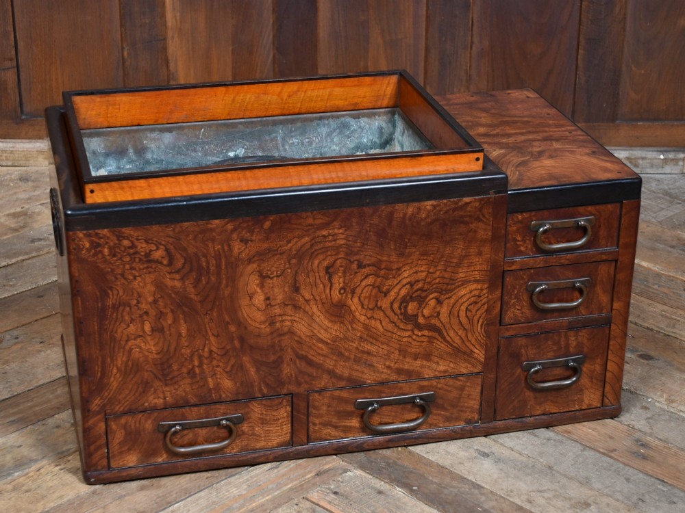 A traditional Japanese wooden hibachi brazier featuring rich figured wood grain, a copper-lined inner well, multiple small drawers, and iron bail handles. View II