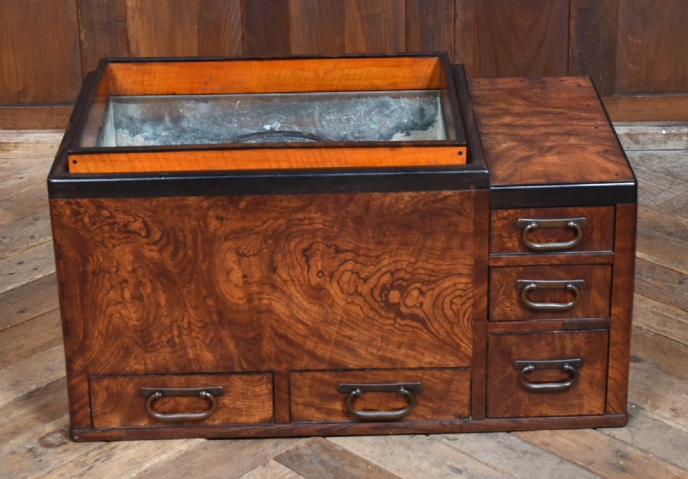 A traditional Japanese wooden hibachi brazier featuring rich figured wood grain, a copper-lined inner well, multiple small drawers, and iron bail handles. View III