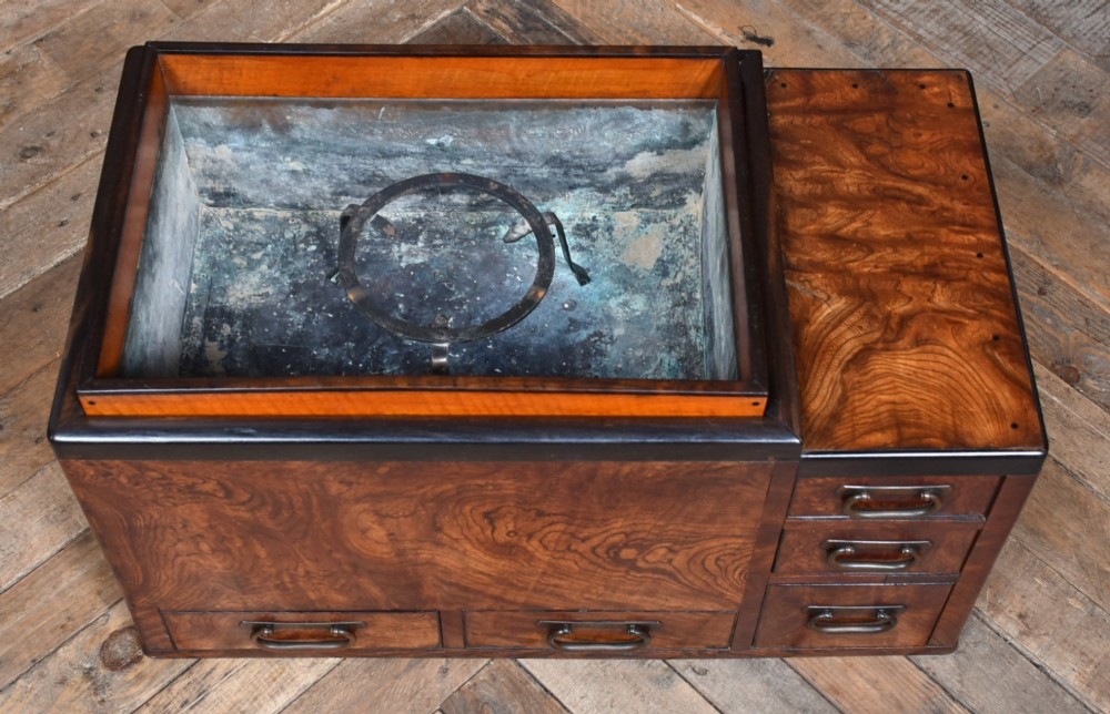 A traditional Japanese wooden hibachi brazier featuring rich figured wood grain, a copper-lined inner well, multiple small drawers, and iron bail handles. View IV