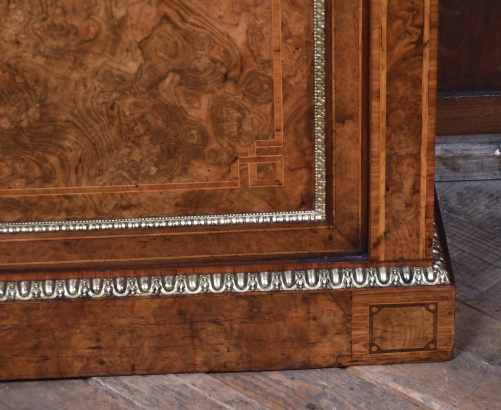 A 19th-century Victorian burr walnut side cabinet featuring two panelled doors with decorative brass mounts and a plinth base. View V