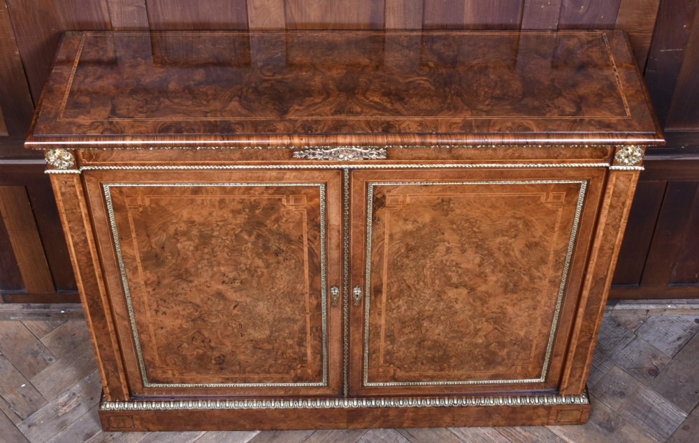 A 19th-century Victorian burr walnut side cabinet featuring two panelled doors with decorative brass mounts and a plinth base. View VIII
