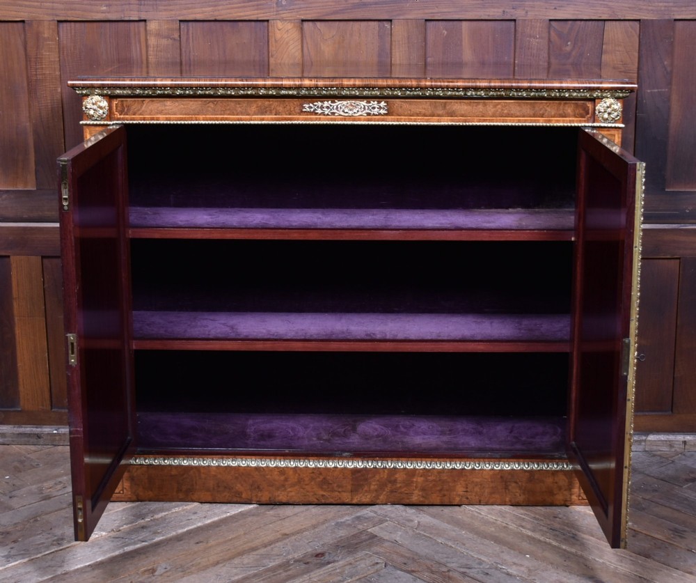 A 19th-century Victorian burr walnut side cabinet featuring two panelled doors with decorative brass mounts and a plinth base. View X