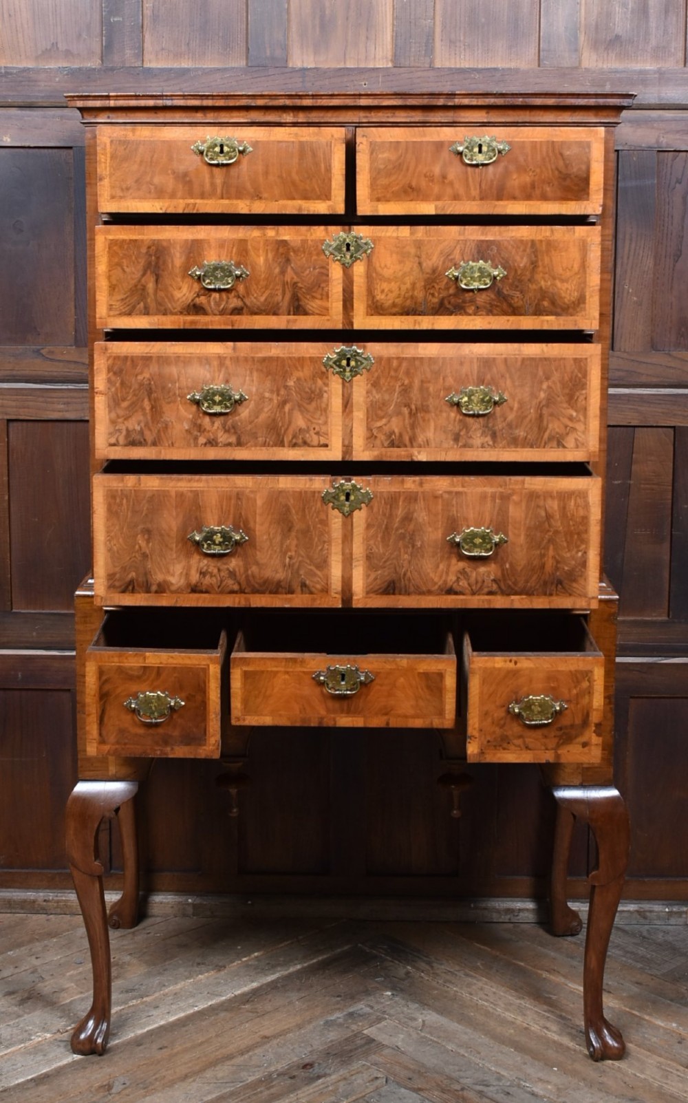 An eighteenth-century figured walnut chest on stand featuring brass hardware, crossbanded drawers, an arched apron, and cabriole legs. View II