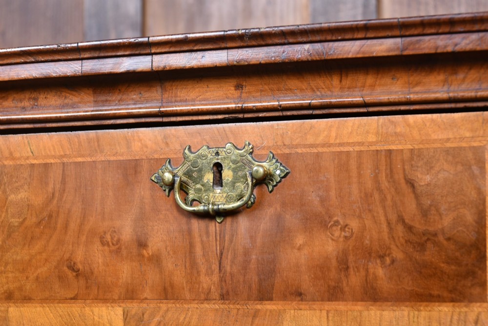 An eighteenth-century figured walnut chest on stand featuring brass hardware, crossbanded drawers, an arched apron, and cabriole legs. View III