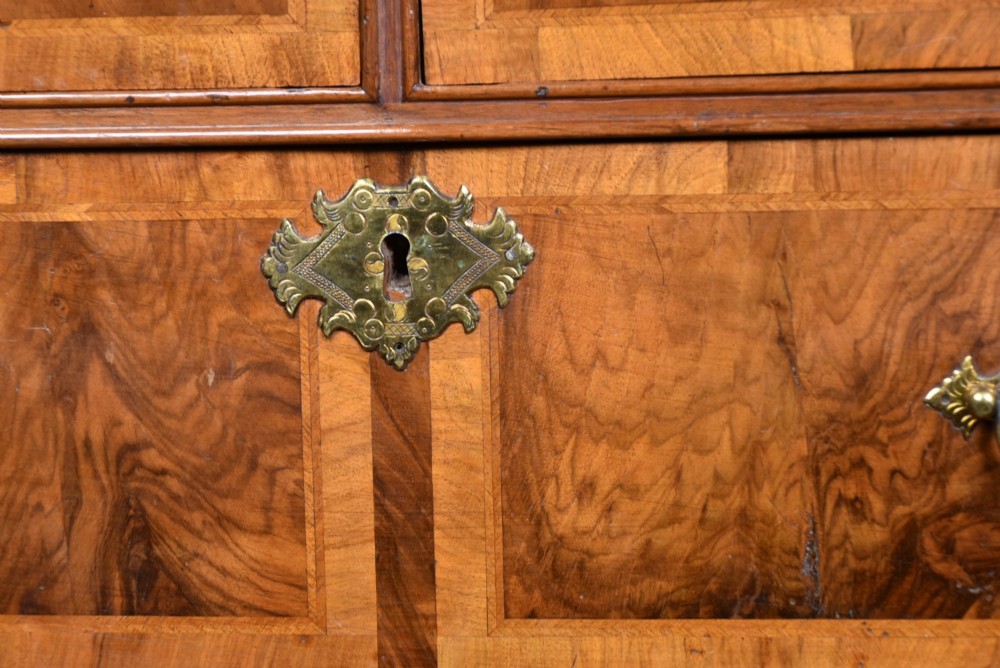 An eighteenth-century figured walnut chest on stand featuring brass hardware, crossbanded drawers, an arched apron, and cabriole legs. View IV