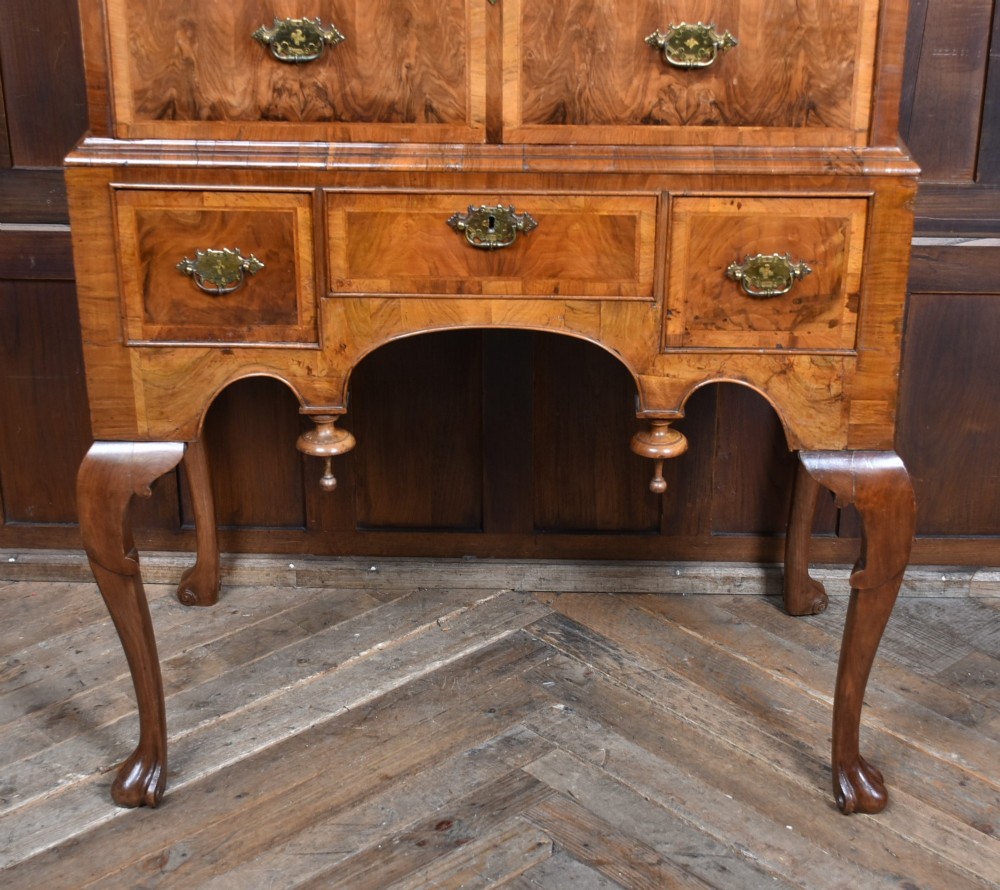 An eighteenth-century figured walnut chest on stand featuring brass hardware, crossbanded drawers, an arched apron, and cabriole legs. View VI