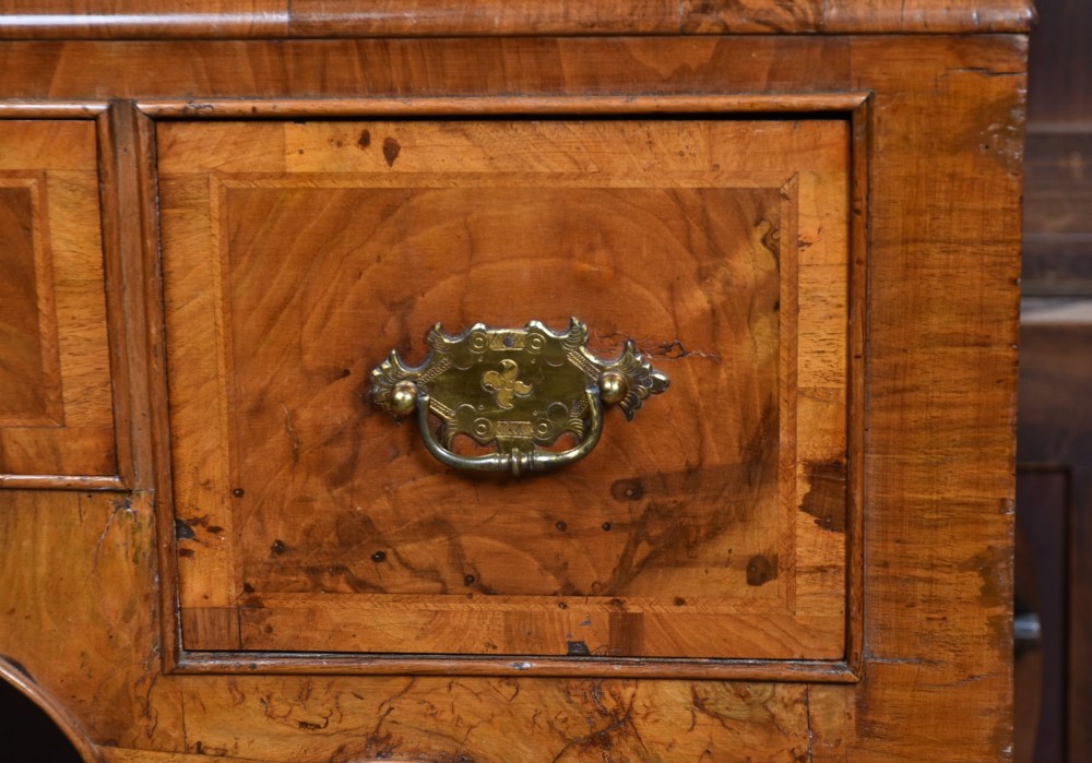 An eighteenth-century figured walnut chest on stand featuring brass hardware, crossbanded drawers, an arched apron, and cabriole legs. View VII