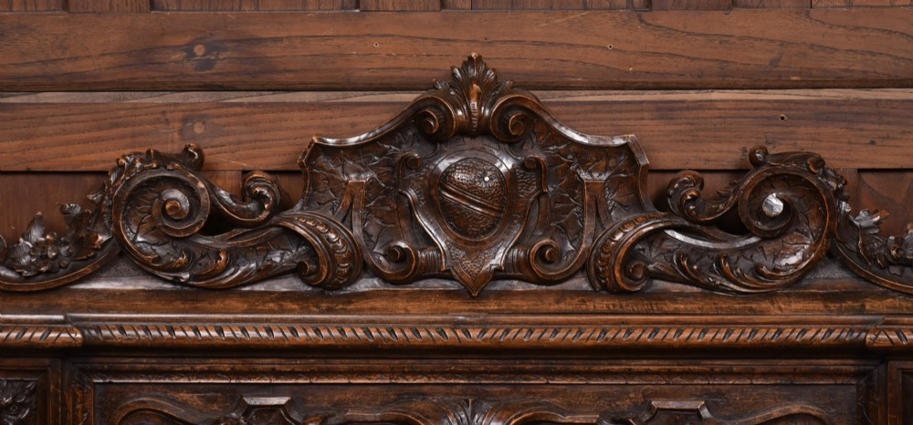 A heavily carved 19th-century Italian walnut cassapanca bench featuring relief panels of cherubs, scrolled cresting, and carved lion armrests. View III