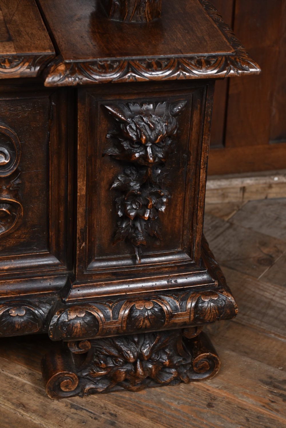 A heavily carved 19th-century Italian walnut cassapanca bench featuring relief panels of cherubs, scrolled cresting, and carved lion armrests. View IX