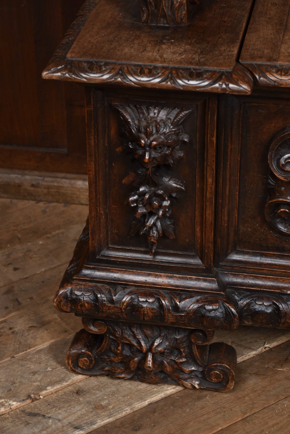 A heavily carved 19th-century Italian walnut cassapanca bench featuring relief panels of cherubs, scrolled cresting, and carved lion armrests. View X