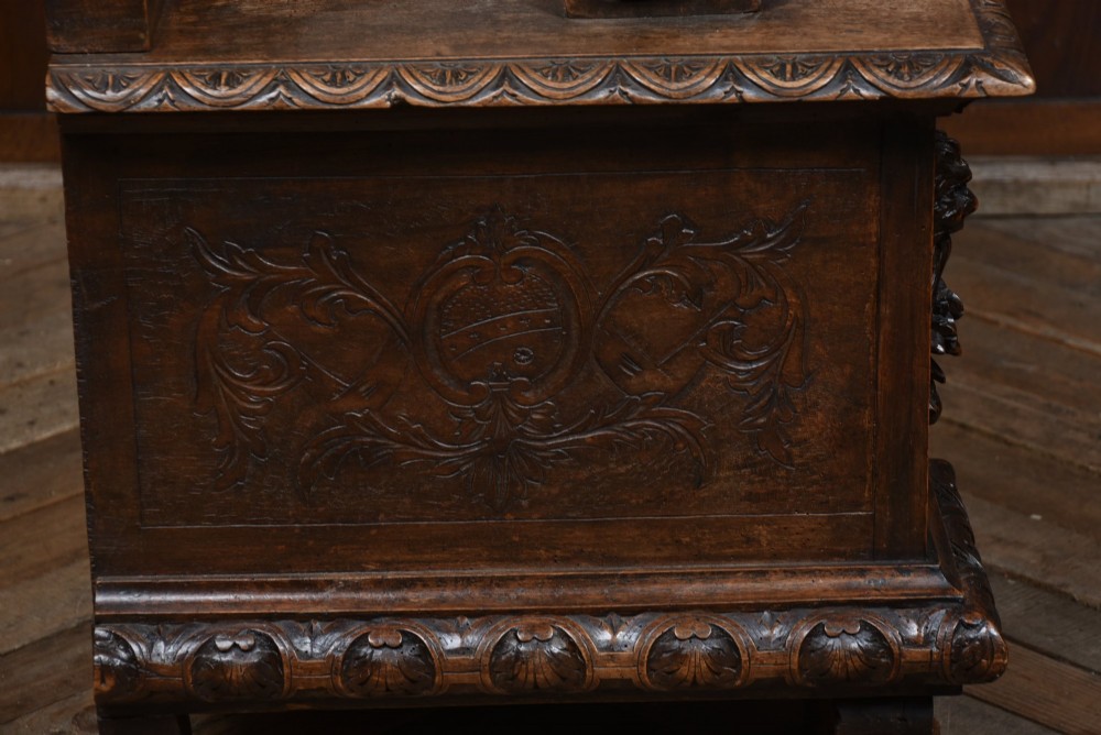 A heavily carved 19th-century Italian walnut cassapanca bench featuring relief panels of cherubs, scrolled cresting, and carved lion armrests. View XII