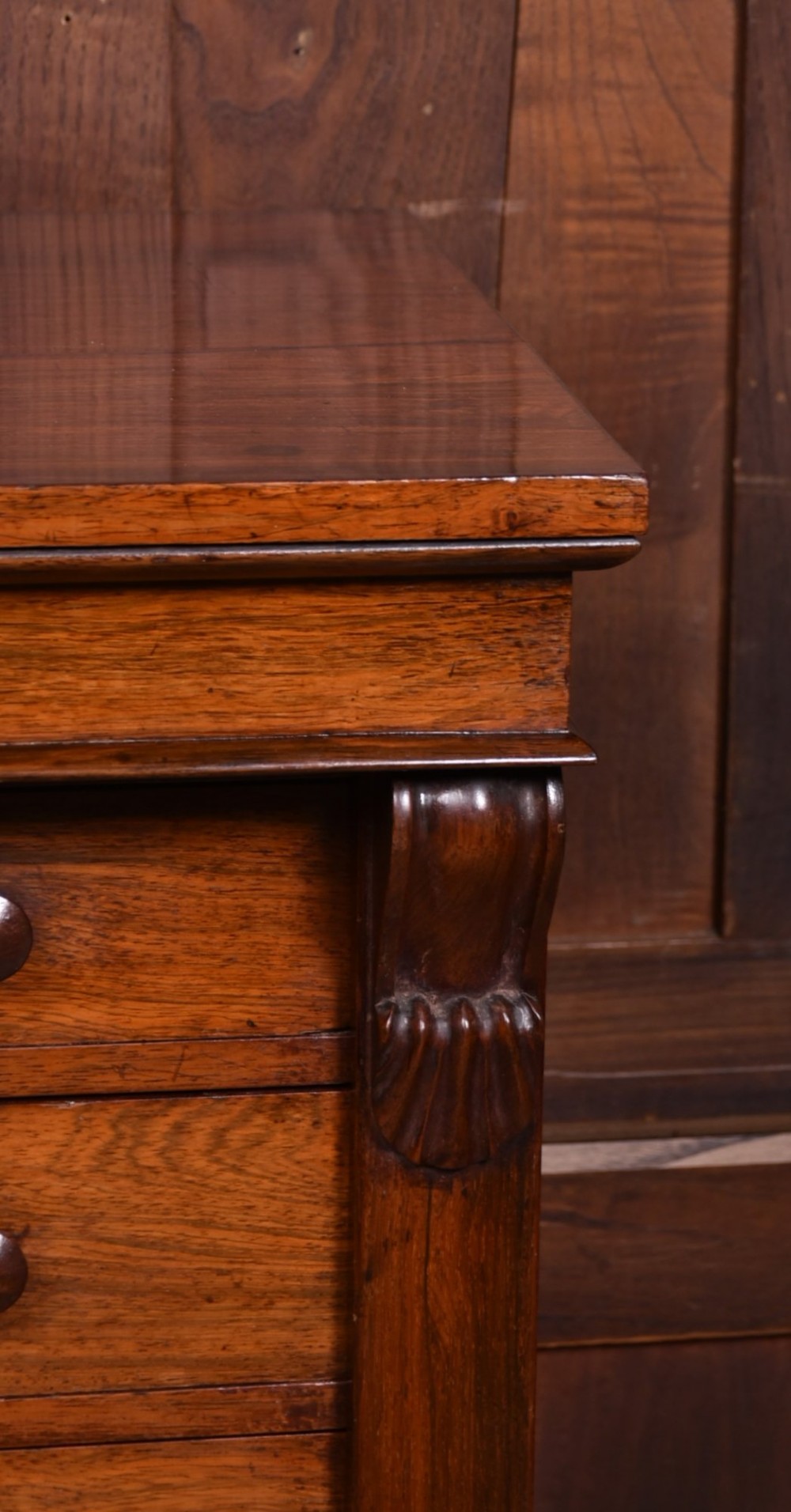 A tall Victorian rosewood Wellington chest featuring six graduated drawers with turned wooden knobs, carved corbels, and a right-side locking bar. View III
