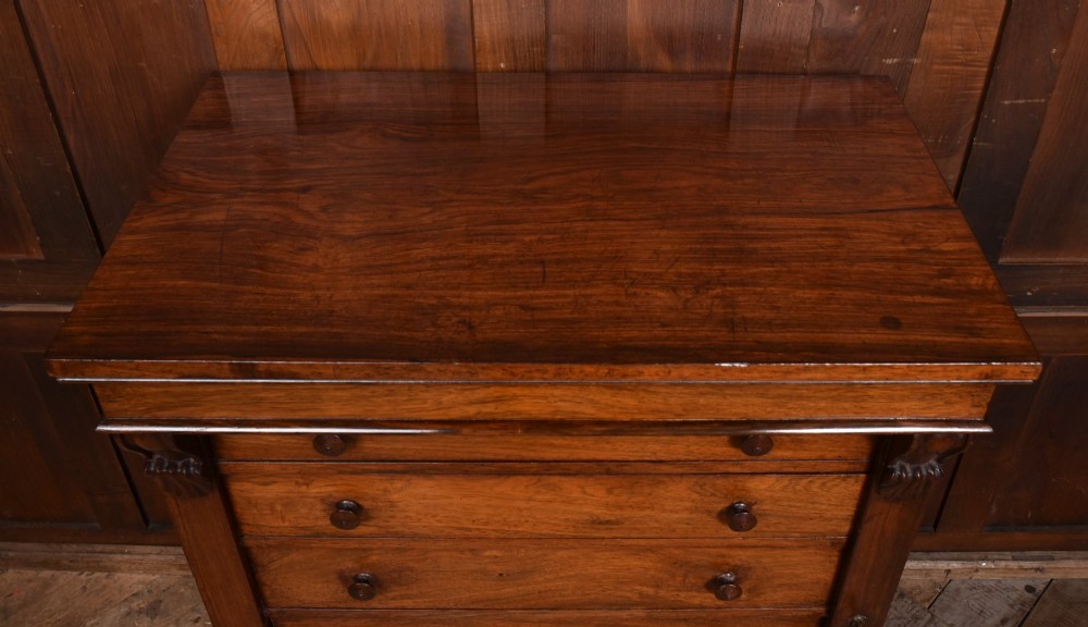 A tall Victorian rosewood Wellington chest featuring six graduated drawers with turned wooden knobs, carved corbels, and a right-side locking bar. View IX
