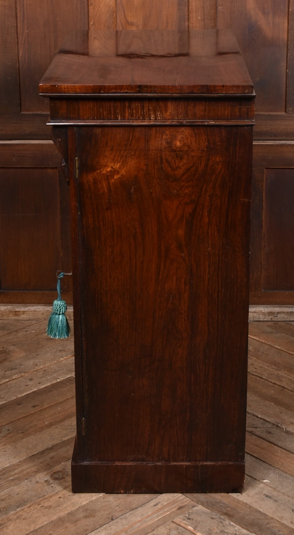 A tall Victorian rosewood Wellington chest featuring six graduated drawers with turned wooden knobs, carved corbels, and a right-side locking bar. View XII