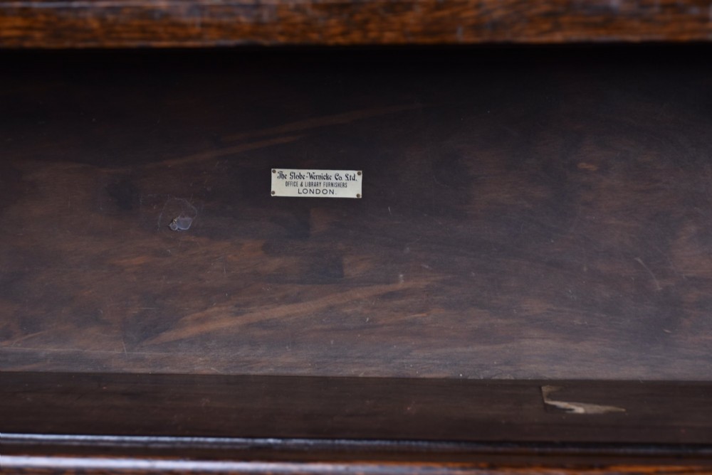 An Edwardian dark oak four-tier Globe Wernicke sectional bookcase featuring glass up-and-over doors and brass maker labels. View VI