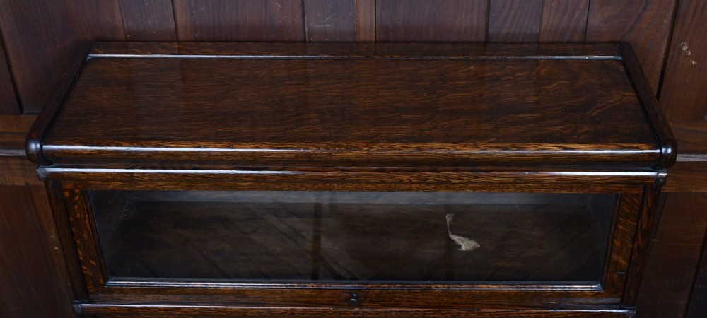 An Edwardian dark oak four-tier Globe Wernicke sectional bookcase featuring glass up-and-over doors and brass maker labels. View IX