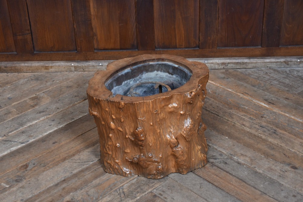 A carved wooden tree-stump hibachi featuring a hollowed centre with a copper lining and iron trivet.