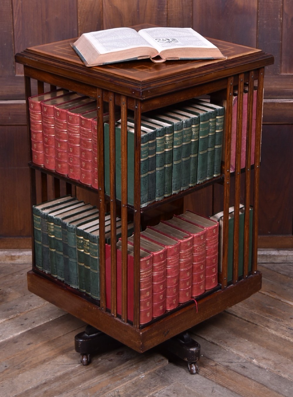 An Edwardian mahogany two-tier revolving bookcase with vertical slatted sides, satinwood top inlay, and a rotating cast-iron base.