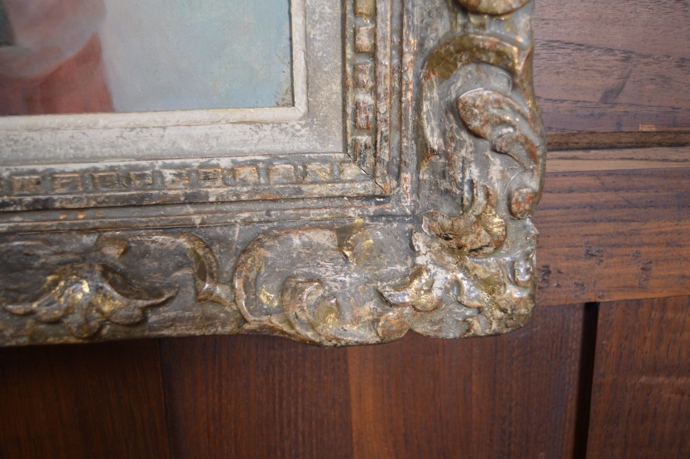 An antique oil painting on canvas depicting a portrait of a dark-haired woman in a soft pink shawl with a red rose, set within an ornate carved gilt frame. View VIII
