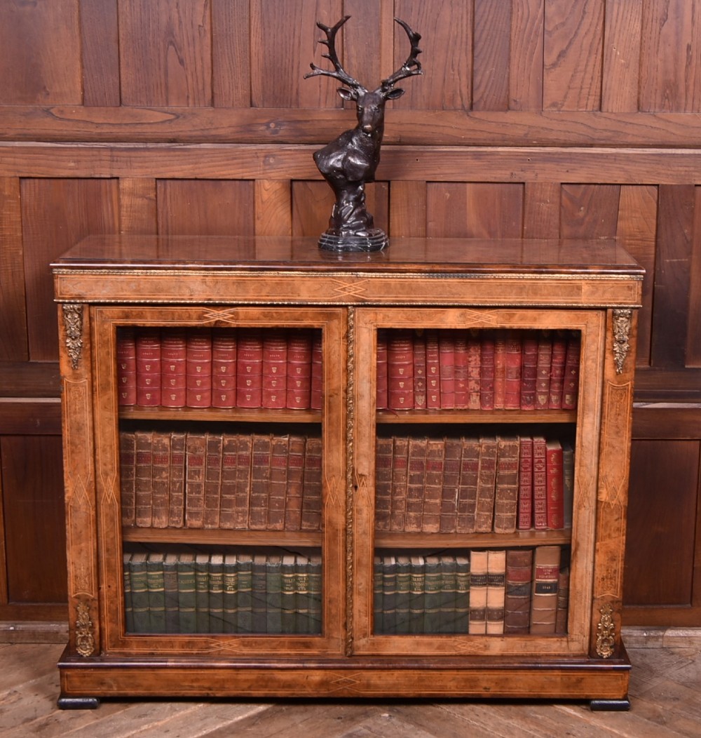 A Victorian burr walnut low cabinet featuring two glazed doors, intricate boxwood inlay, and ornate bronzed corner mounts.