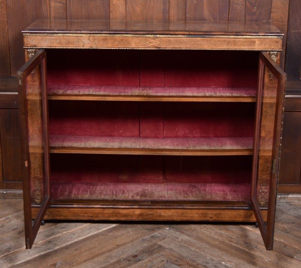 A Victorian burr walnut low cabinet featuring two glazed doors, intricate boxwood inlay, and ornate bronzed corner mounts. View VII