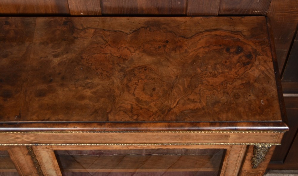 A Victorian burr walnut low cabinet featuring two glazed doors, intricate boxwood inlay, and ornate bronzed corner mounts. View XI