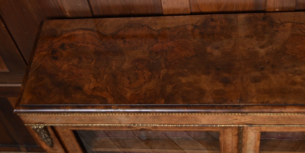 A Victorian burr walnut low cabinet featuring two glazed doors, intricate boxwood inlay, and ornate bronzed corner mounts. View XII