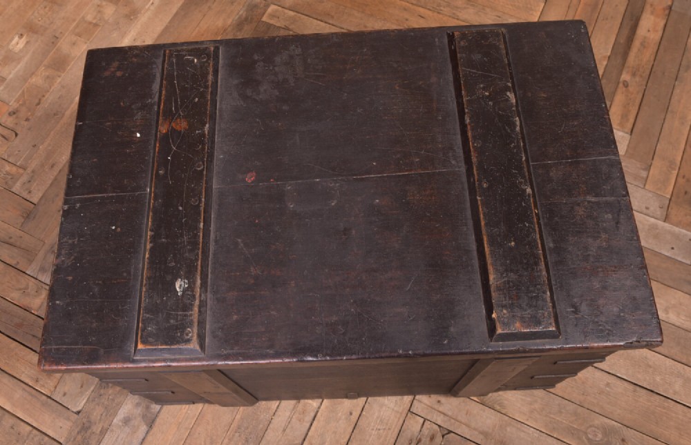 A rectangular dark brown 19th-century teak storage chest featuring heavy iron corner brackets, side handles, and a hinged flat lid. View II