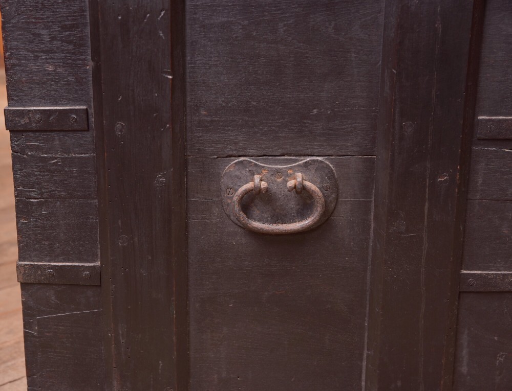 A rectangular dark brown 19th-century teak storage chest featuring heavy iron corner brackets, side handles, and a hinged flat lid. View VI