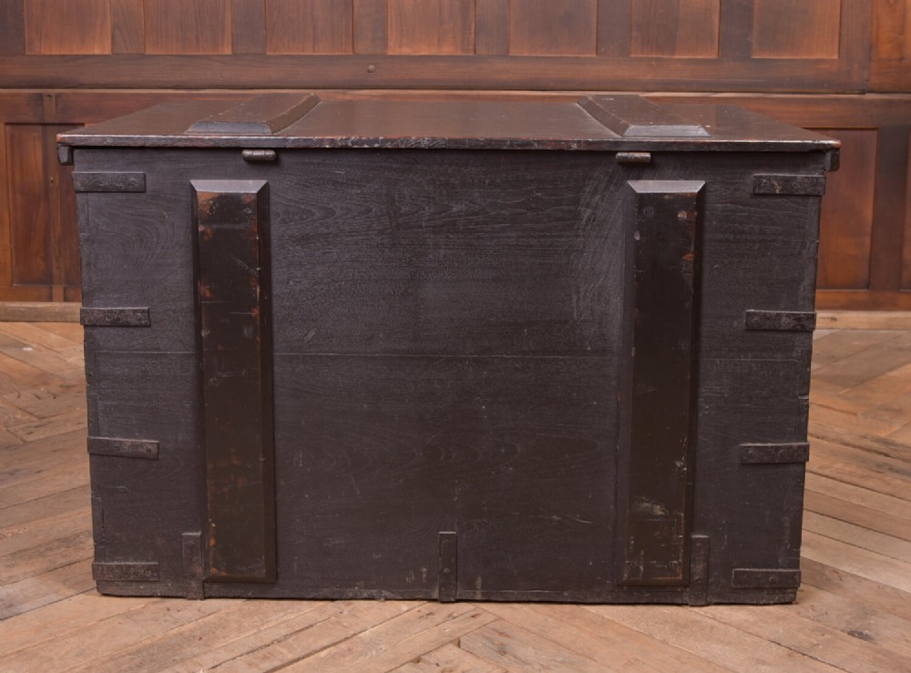 A rectangular dark brown 19th-century teak storage chest featuring heavy iron corner brackets, side handles, and a hinged flat lid. View VII