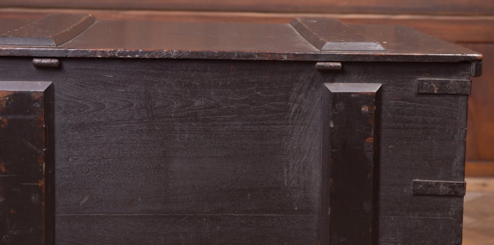 A rectangular dark brown 19th-century teak storage chest featuring heavy iron corner brackets, side handles, and a hinged flat lid. View VIII