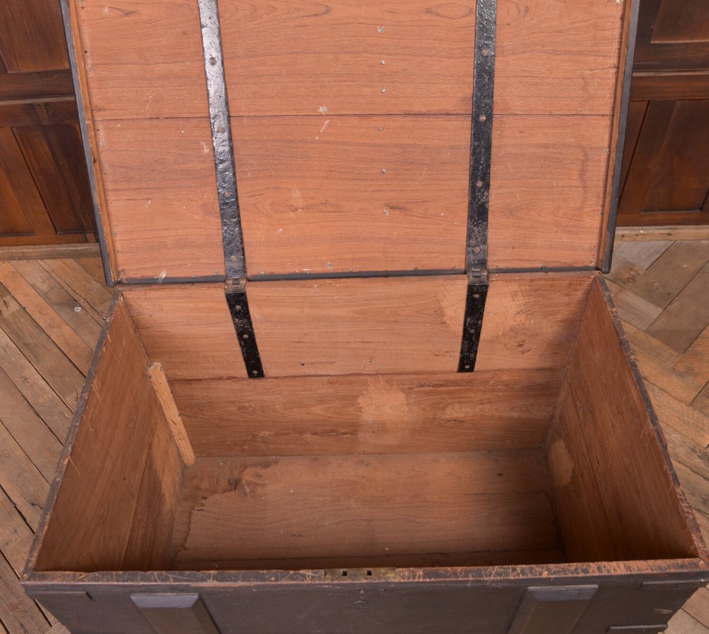 A rectangular dark brown 19th-century teak storage chest featuring heavy iron corner brackets, side handles, and a hinged flat lid. View IX