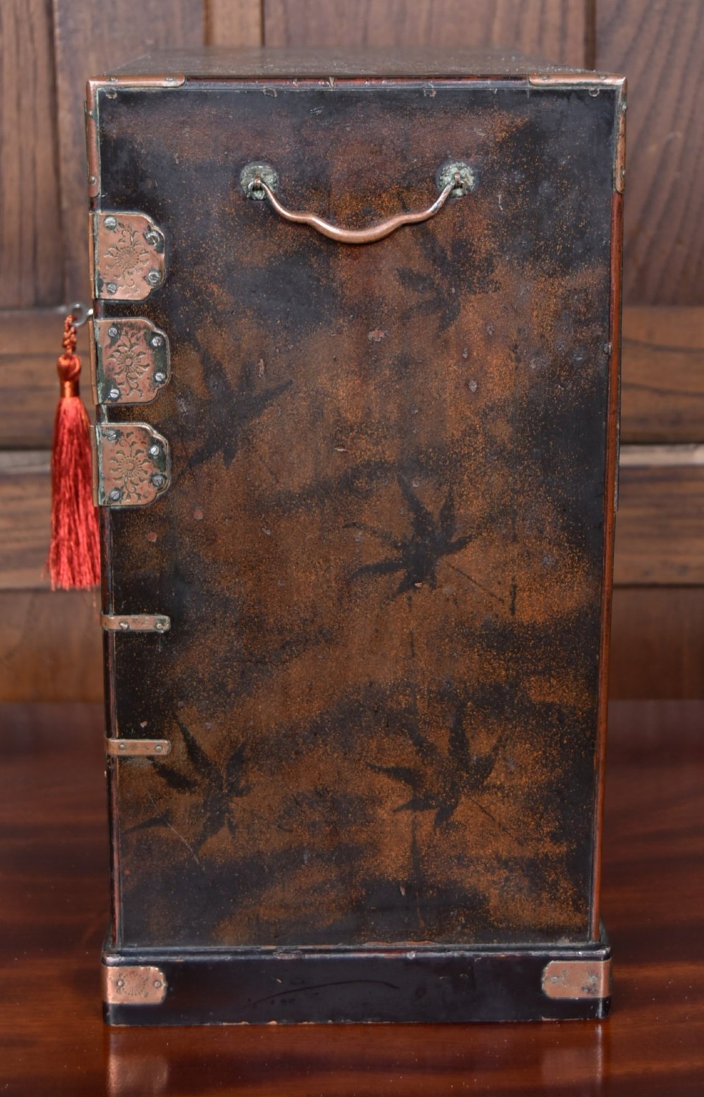 A Japanese tabletop wooden kodansu cabinet featuring geometric marquetry, mother-of-pearl shell inlay on dark lacquered door panels, metal mounts, and lower drawers. View X