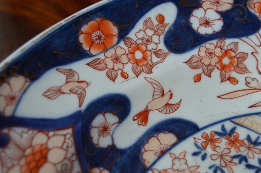 A circular Japanese Imari porcelain plate decorated in cobalt blue, iron-red, and gold floral patterns around a central floral roundel. View IV