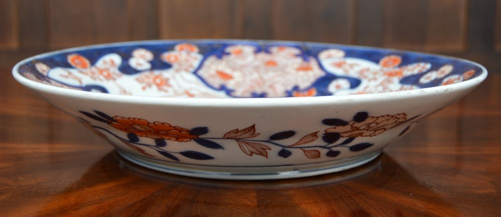 A circular Japanese Imari porcelain plate decorated in cobalt blue, iron-red, and gold floral patterns around a central floral roundel. View V