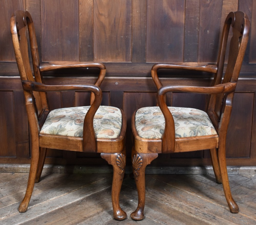 A pair of Victorian Queen Anne style walnut armchairs featuring vase-shaped back splats, carved cabriole legs, and floral patterned drop-in seats. View IX